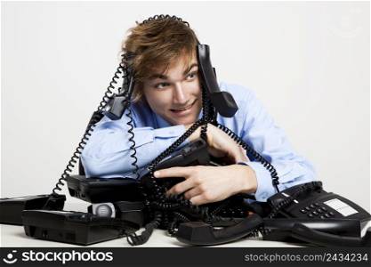 Young man sitting with a bunch of phones over him