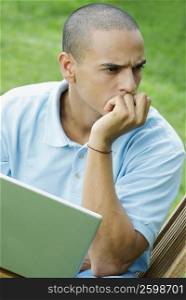 Young man sitting with a laptop and thinking