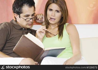 Young man sitting with a young woman reading a book