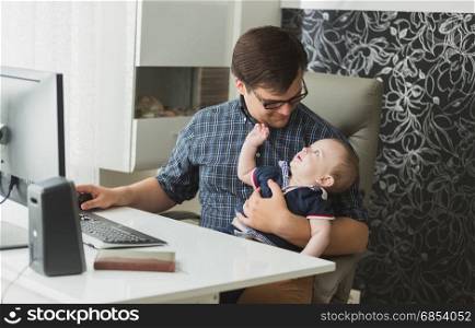 Young man sitting with his baby and working at home