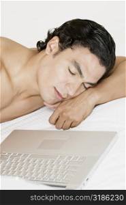 Young man sleeping in front of a laptop