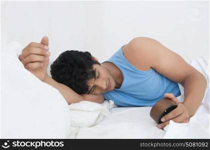 Young man sleeping while holding clock