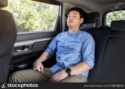 young man sleeping while sitting in the back seat of car
