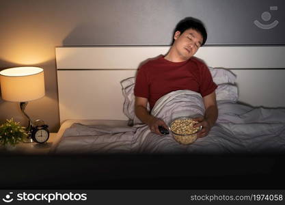 young man sleeping while watching tv on a bed at night