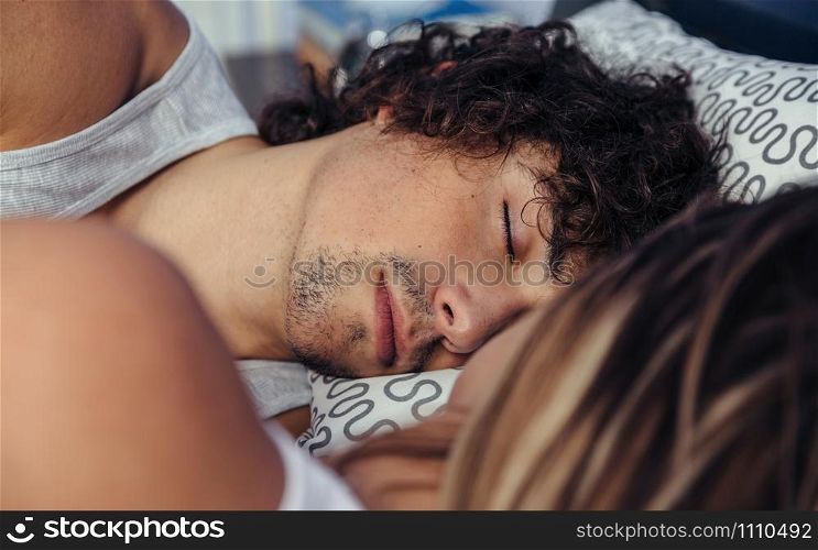 Young man sleeping with his partner in bed