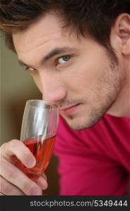 Young man smelling a glass of rose