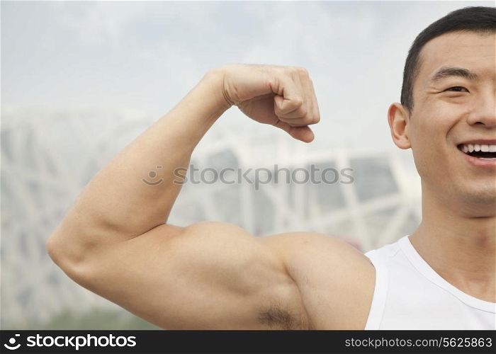 Young man smiling and flexing his bicep