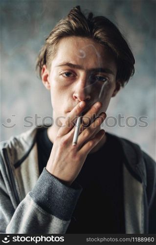 Young man smoke cigarette, grunge background. Addiction concept, smoking drugs. Young man smoke cigarette, addiction concept