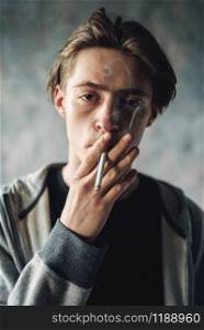 Young man smoke cigarette, grunge background. Addiction concept, smoking drugs. Young man smoke cigarette, addiction concept