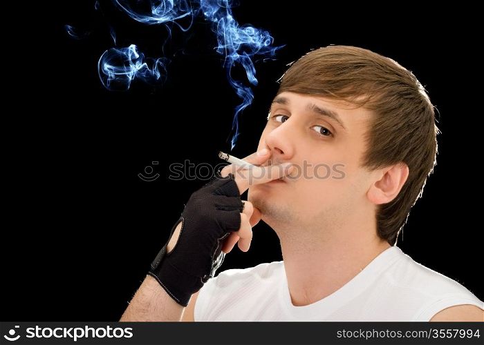Young man smoking a cigarette. Isolated on black