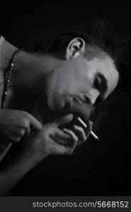 young man smoking cigarette on black background