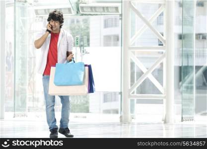 Young man speaking on phone with shopping bags