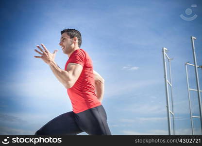 Young man sprinting against blue sky