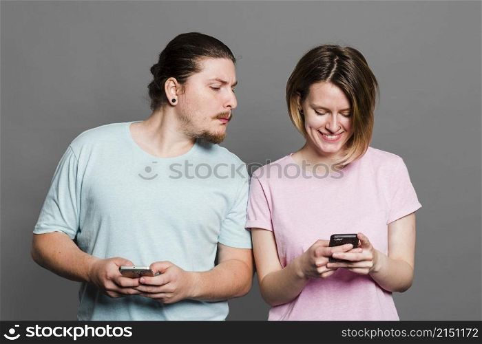 young man spying peeking smartphone her girlfriend using mobile phone