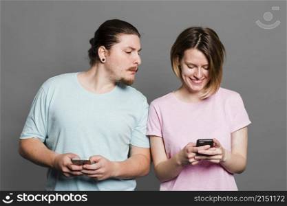 young man spying peeking smartphone her girlfriend using mobile phone