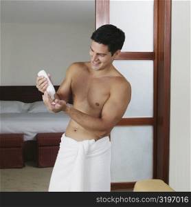 Young man squeezing a bottle of moisturizer on his palm