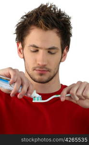 Young man squeezing toothpaste onto a brush