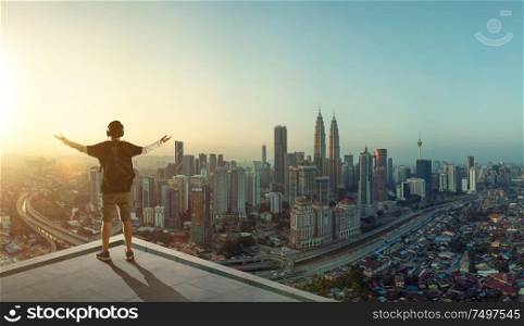 Young man stand at rooftop looking great cityscape sunrise view and praying .