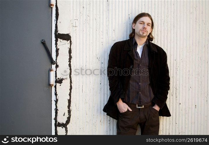 Young man standing against wall, portrait