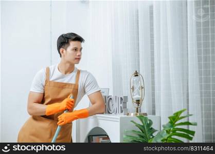 Young man standing and hold mop in hand looking around living room after finish cleaning with proud, copy space