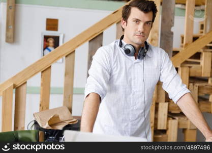 Young man standing in creative office. Smiling young designer standing in creative office in front of his desk