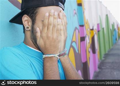 Young man standing in front of graffiti wall