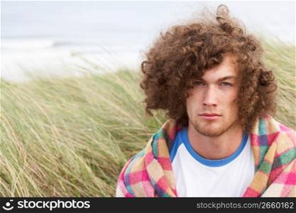 Young Man Standing In Sand Dunes Wrapped In Blanket