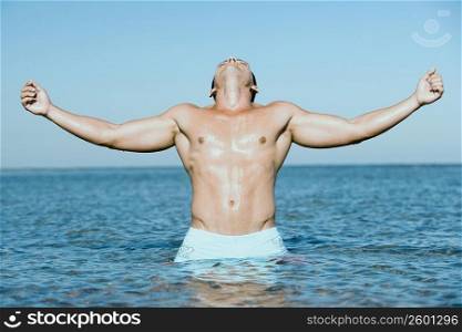 Young man standing in water with his arms outstretched