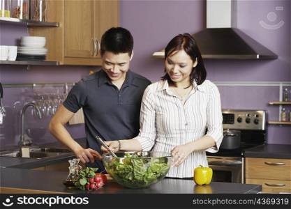 Young man standing looking at a young woman preparing food