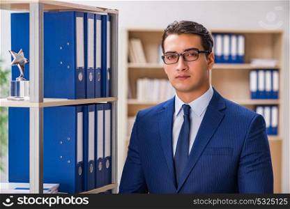 Young man standing next to the shelf with folders