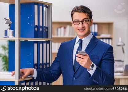 Young man standing next to the shelf with folders