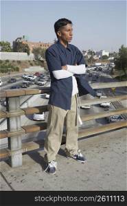 Young man standing on an overpass with arms crossed