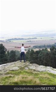 Young Man Standing On Rock With Outstretched Arms