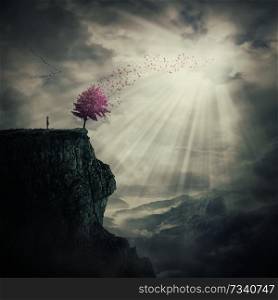 Young man standing on the peak of a cliff watching at a strange, purple tree that cast its leaves in the wind over valley. The tree of life symbol, journey and discover.