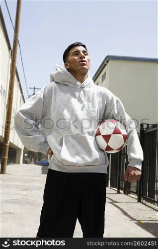 Young man standing on the street holding a soccer ball