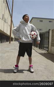 Young man standing on the street holding a soccer ball