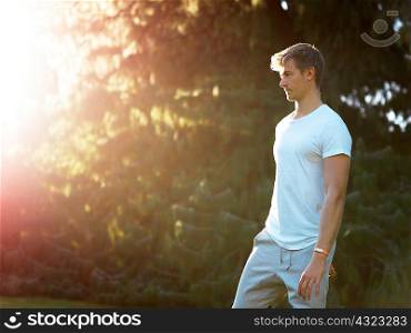 Young man standing outdoors, looking away