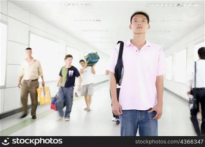Young man standing with a bag in a corridor