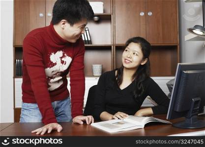 Young man standing with a mid adult woman sitting beside him smiling