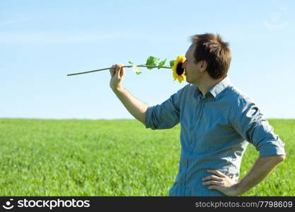 young man standing with a sunflower in the green field