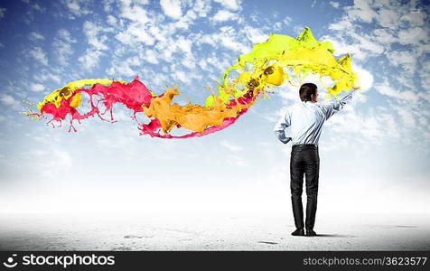 young man standing with back painting splashes with fingers