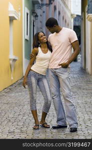 Young man standing with his arm around a teenage girl