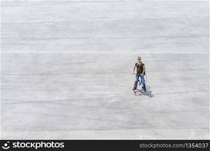 Young man standing with his bike on a square ( Copyspace )