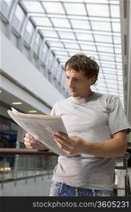 Young man stands reading newspaper in new shopping centre Voronezh