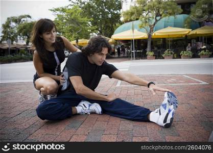 Young man stretching with physical trainer