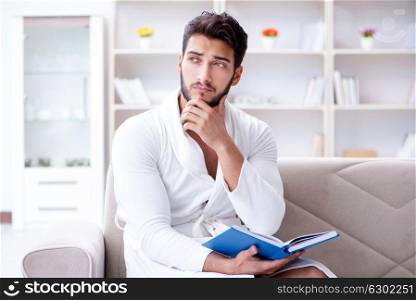 Young man student businessman reading a book studying working at. Young man student businessman reading a book studying working at home