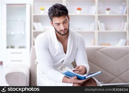 Young man student businessman reading a book studying working at. Young man student businessman reading a book studying working at home