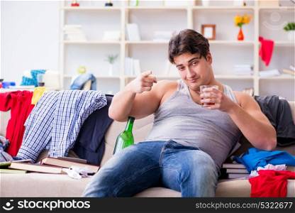 Young man student drunk drinking alcohol in a messy room