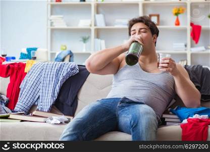 Young man student drunk drinking alcohol in a messy room