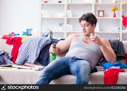 Young man student drunk drinking alcohol in a messy room